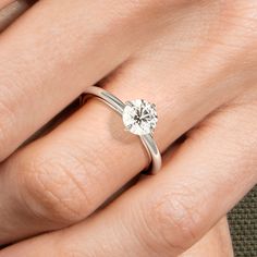 a woman's hand with a white diamond ring on her finger, close up