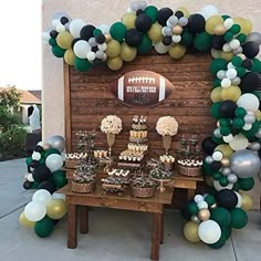 a football themed dessert table with balloons and cupcakes