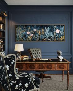 an office with blue walls and floral paintings on the wall, along with a leather chair