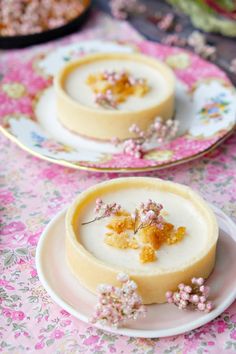 two plates with small desserts on them sitting on a table covered in pink flowers