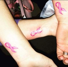 two people with matching pink ribbon tattoos on their arms and ankles, both holding hands together