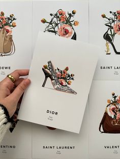 a person holding up a card with shoes and flowers on it, in front of several other cards