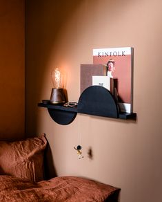 a bed with a brown comforter and a black shelf on the wall above it