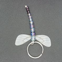 a keychain with beads and wings attached to it on a gray cloth background