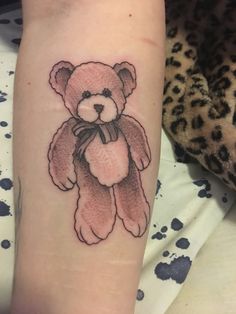 a small teddy bear tattoo on the arm