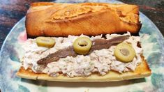 a sandwich on a plate with olives and meat