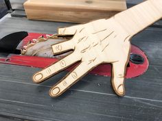 a wooden hand that is on top of a piece of wood next to some tools