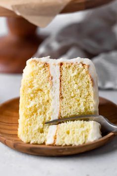 a slice of white cake on a plate with a fork in front of the rest of the cake