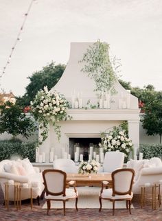 an outdoor dining area with white furniture and flowers