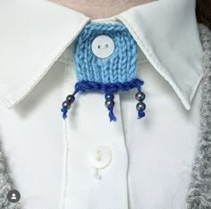 a close up of a person wearing a white shirt and blue tie with buttons on it