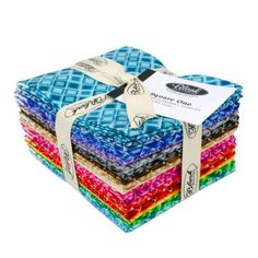 a stack of multicolored quilts with a ribbon