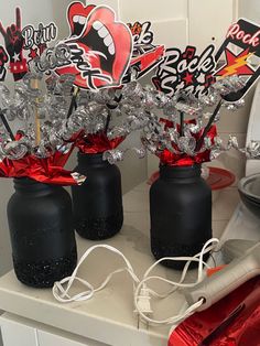 three black vases with red and silver decorations in them on a counter top,