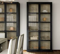 an empty dining room table and chairs in front of glass cabinets