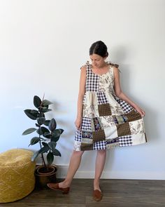 a woman standing next to a potted plant wearing a dress made from patchwork fabric