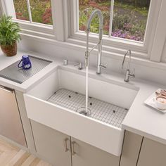 a white kitchen sink sitting under a window next to a potted plant on top of a counter