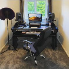 a computer desk with a keyboard and speakers in front of a large window on the wall