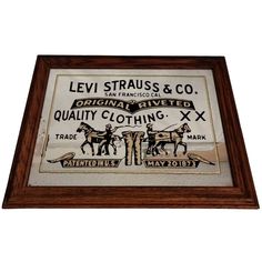 an old advertisement for levi strauss & co hangs in a wooden frame on the wall