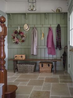 a coat rack with baskets and coats hanging on the wall next to a wooden bench