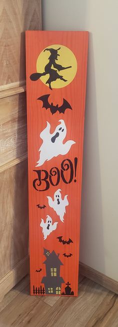 a wooden sign that says boo with ghostes and bats on it, in front of a wall