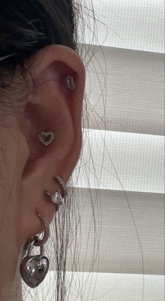 a close up of a person's ear with earrings on it and blinds behind them