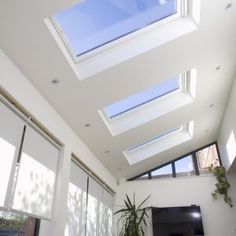 a living room filled with lots of windows next to a white wall and ceiling mounted flat screen tv