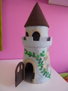 a small castle made out of felt on top of a white table next to a pink wall