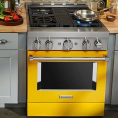 a yellow stove top oven sitting inside of a kitchen next to a counter with pots and pans on it