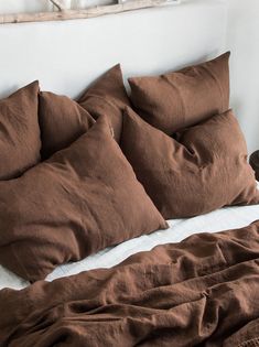 the bed is made with brown linens and pillows