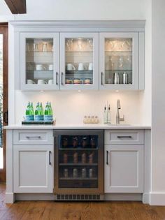 a kitchen with white cabinets and glass doors on the cupboards are filled with dishes