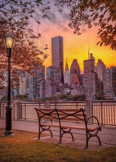 a park bench sitting next to a lamp post in front of a cityscape