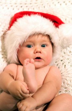 a baby wearing a santa hat on top of a white blanket