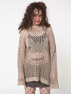 a woman with curly hair wearing tights and a knitted sweater is standing in front of a white wall