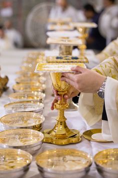 a person holding a chalice in front of a table full of plates and bowls