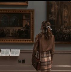 a woman standing in front of a painting and looking at the paintings on the wall