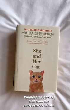 the book she and her cat is sitting on top of a bed with white sheets