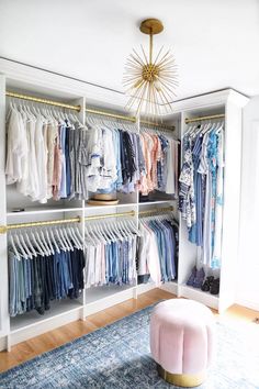 a walk in closet with clothes on hangers and a rug underneath the chandelier