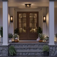 the front porch is lit up with pumpkins and greenery