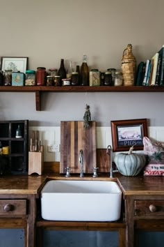 a kitchen sink sitting under a wooden shelf