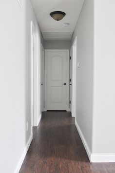 an empty hallway with white walls and wood flooring is seen in this image from the front door