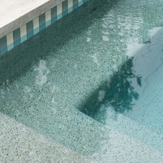 an empty swimming pool with blue tiles and water reflecting off the side of it's surface