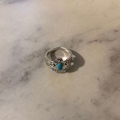 a silver ring with a turquoise stone in the middle on a marble countertop top