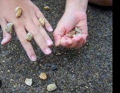 two hands reaching for rocks on the ground with one hand holding another's fingers