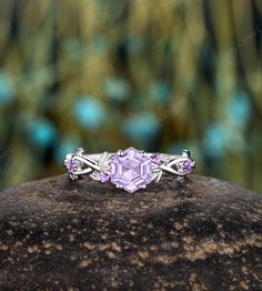 a ring with an amethorate stone in the center on top of a rock