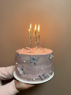 a person holding a cake with lit candles on it