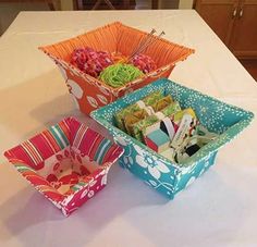 three colorful bowls are sitting on a white table cloth covered table with crochet hooks in them