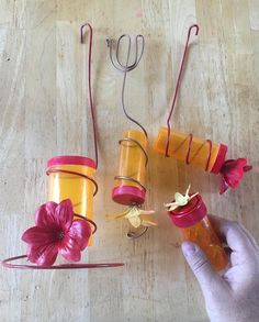 a person holding two jars with flowers in them and string attached to the top one