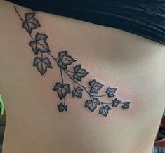 a woman's lower back tattoo with leaves on her stomach and the word love written in black ink