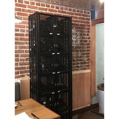 a room with a brick wall and several shelves filled with wine bottles on the floor