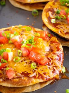 three quesadillas with cheese, tomatoes and green onions on a baking sheet