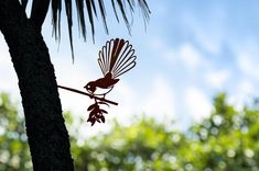 a metal bird sitting on top of a tree branch